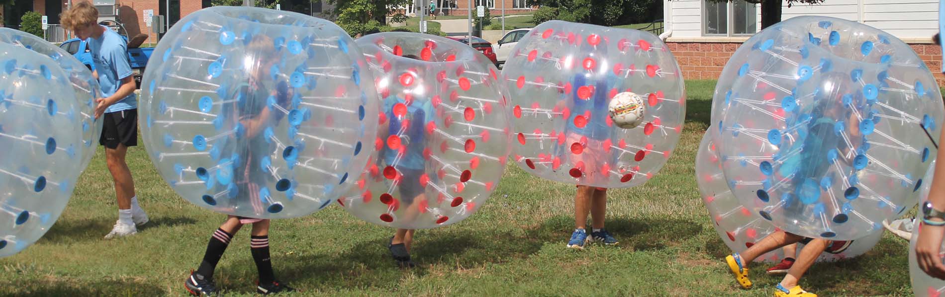 Photo of kids playing bubble soccer with the ball in mid air